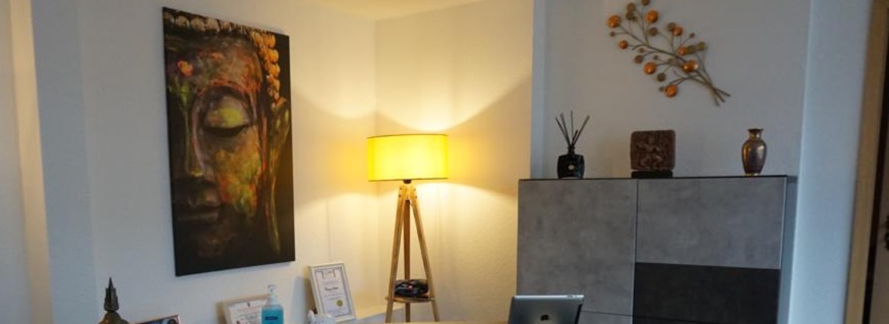 Empfangsbereich im Studio Auszeit mit Buddha-Bild und Stehlampe