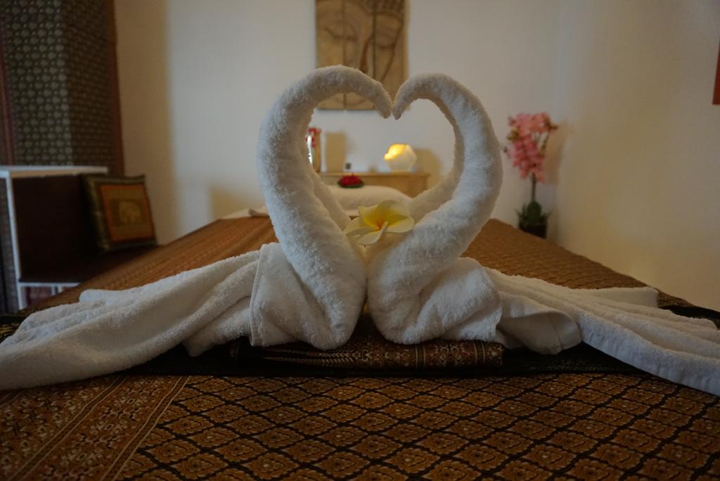 Handtuch-Schwäne mit Blüte auf der Massageliege